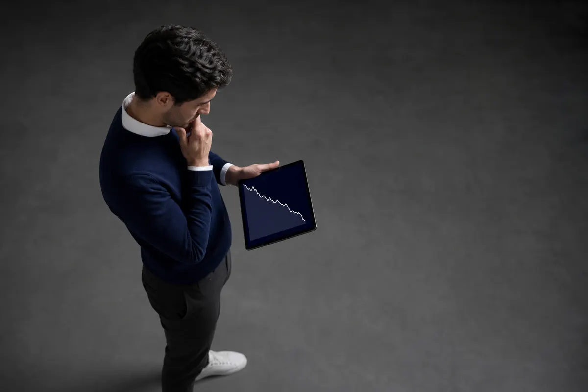 Uma pessoa olhando pensativamente para um gráfico de desempenho em um tablet.