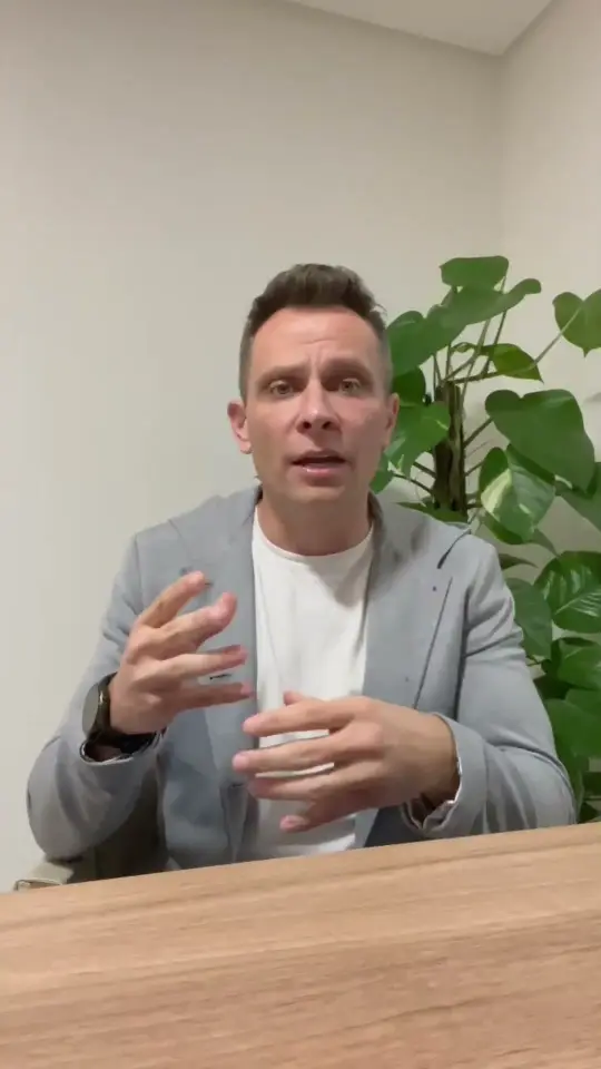 Porta-voz da Dom Negócios Imobiliários falando à câmera em uma mesa de reunião, em frame do depoimento em vídeo